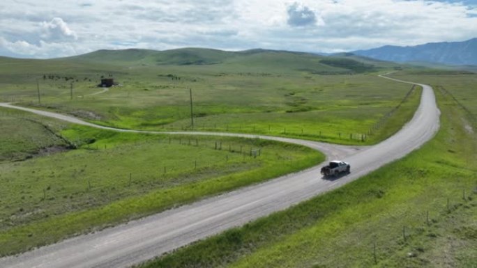 皮卡车沿着乡村公路驶向山脉的鸟瞰图