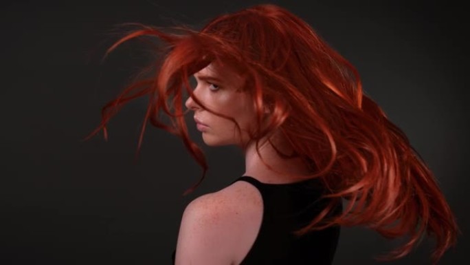 迷人的红头发女人扔她闪亮的长发。
