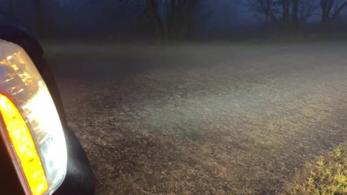 傍晚在乡村道路上雾中汽车前灯发出的光。