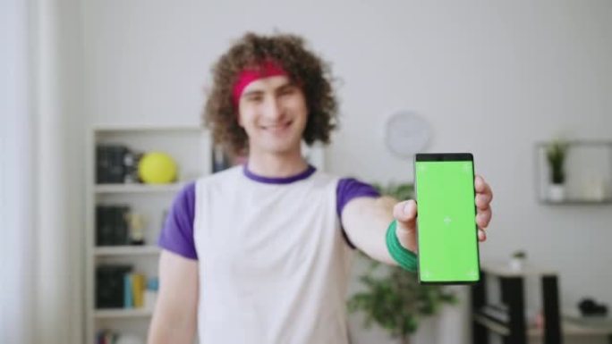 微笑的男人体育迷展示带有预键屏幕的智能手机，体育投注