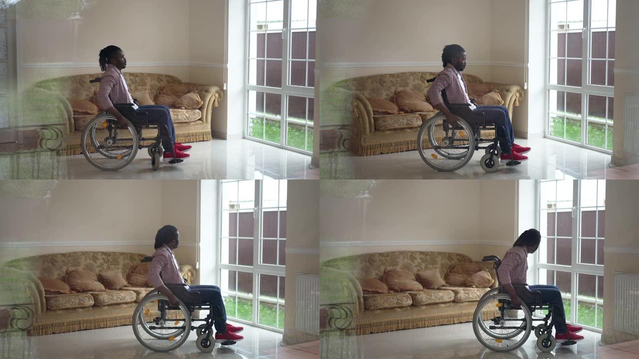 非洲裔美国残疾人以慢动作将手动轮椅滚动到门，看着窗外。大镜头侧视瘫痪在家里客厅的家伙。透过玻璃射击。