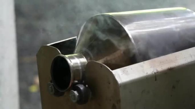 不锈钢咖啡烘焙机通过在高温下以恒定速度使用手摇曲柄。从烟囱中吹出的咖啡壳以及燃烧产生的烟雾。