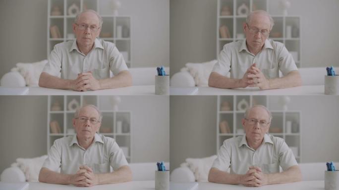 老人的肖像看着相机和点头，在视频聊天中聆听的人，中等镜头