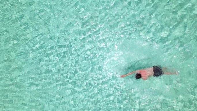 俯视图，亚洲男子在一个大游泳池游泳。