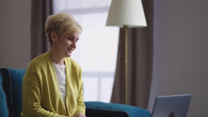 金发碧眼的退休妇女独自坐在家里，通过在线视频聊天与朋友交流，室内老太太的肖像