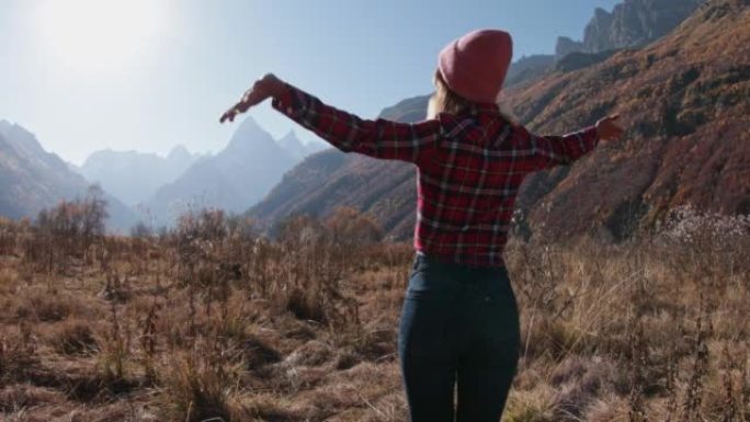 年轻女子在秋山享受。山地和快乐徒步旅行者