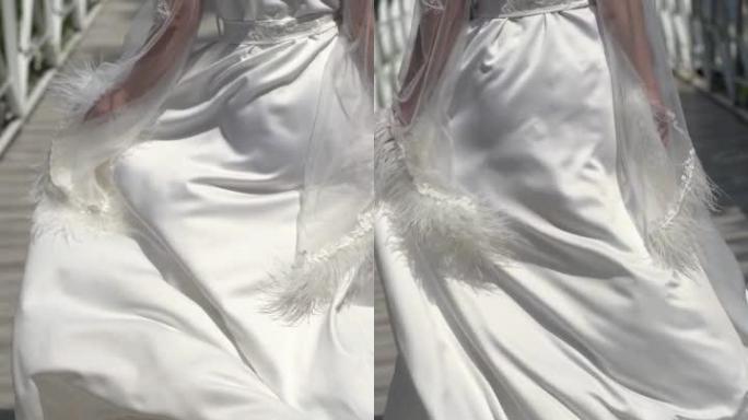 垂直夹。新娘穿着漂亮的拖尾婚纱浴袍，沿着桥走。慢性