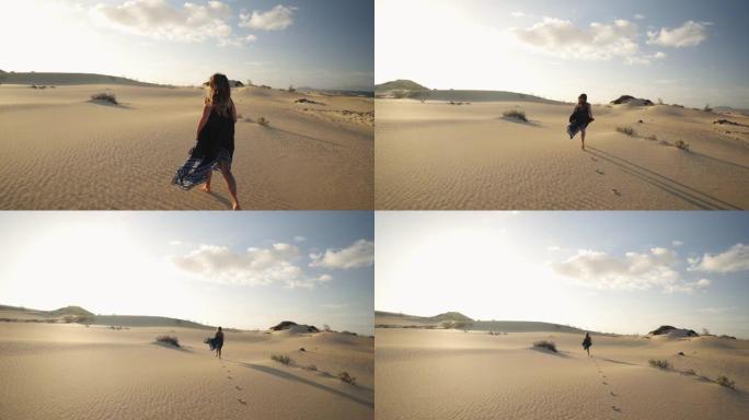 一个穿着黑色连衣裙的女人在沙丘上逃离相机的细节镜头