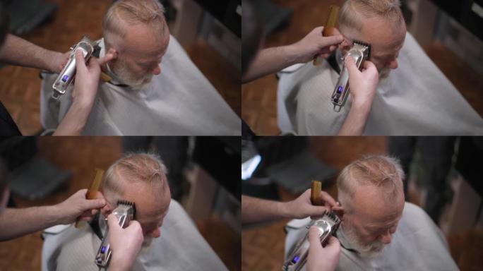 理发店，现代美发师在理发店用修剪器给一位年长的男性客户理发，特写
