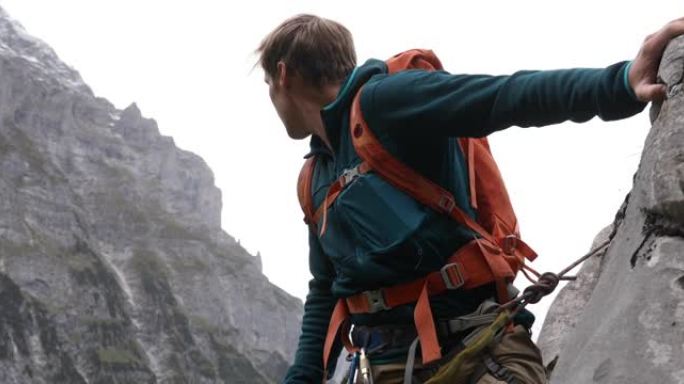 男性登山者登上陡峭的岩石面