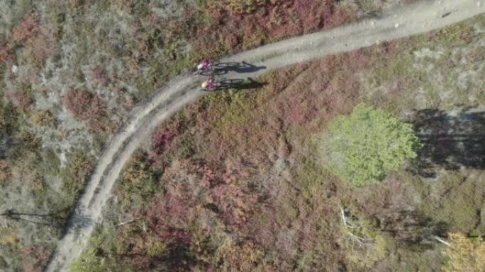 在广阔的荒野中，一对山地自行车夫妇的空中无人机拍摄