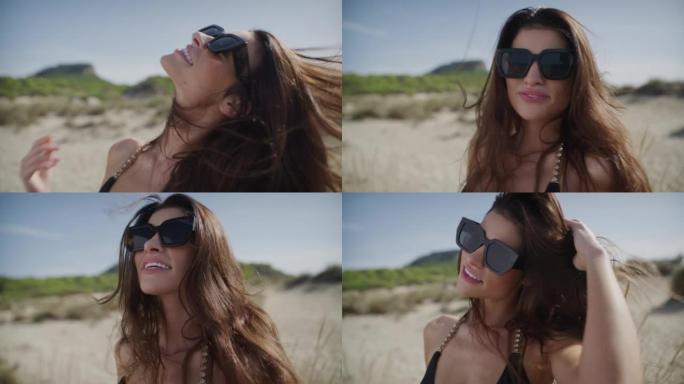 在刮风的海滩上度假时戴着墨镜的年轻女子