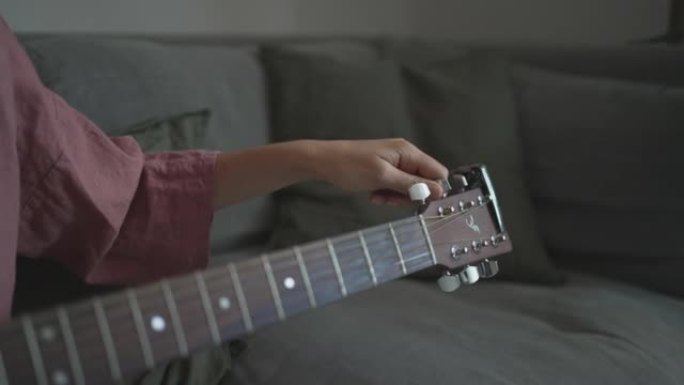 年轻女子在客厅里调音吉他