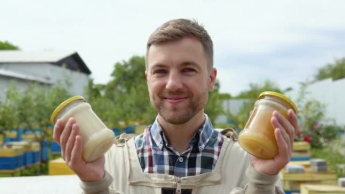 养蜂人的肖像，带有两个装有新鲜蜂蜜的罐子。养蜂概念。养蜂人收获蜂蜜