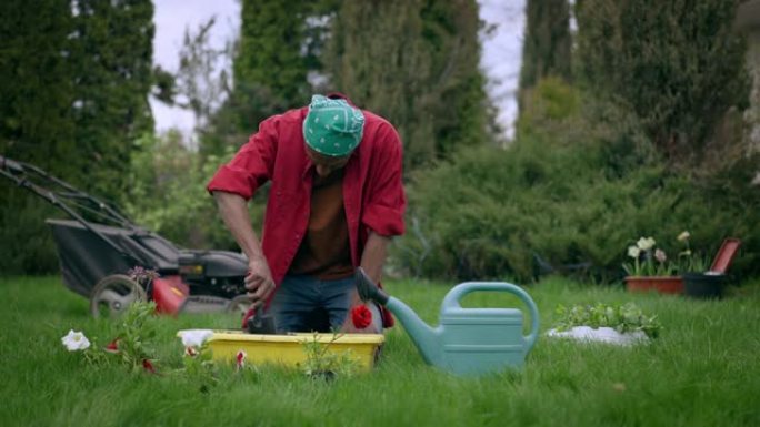 非裔美国男性花店用小铲子在花盆中松动土壤。集中的年轻人在户外花园手工工作的肖像。植物学和园林绿化概念