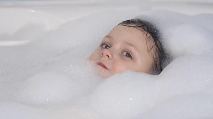 孩子洗澡。浴室里穿着泡沫的快乐小女孩