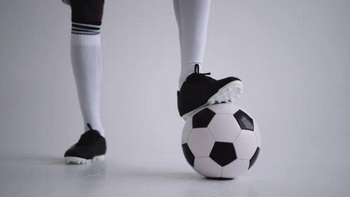 工作室里穿着靴子和膝盖袜子的足球球和腿，特写镜头