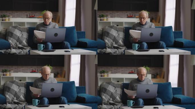 孤独的退休男子正在查看坐在公寓里的文件，使用笔记本电脑进行检查，在家远程工作