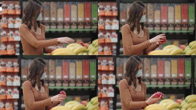 一名戴着口罩的妇女在超市挑选冠状病毒流行的水果和蔬菜