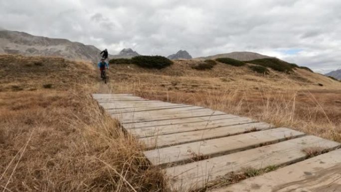 山地自行车手在山地草甸横穿木板路