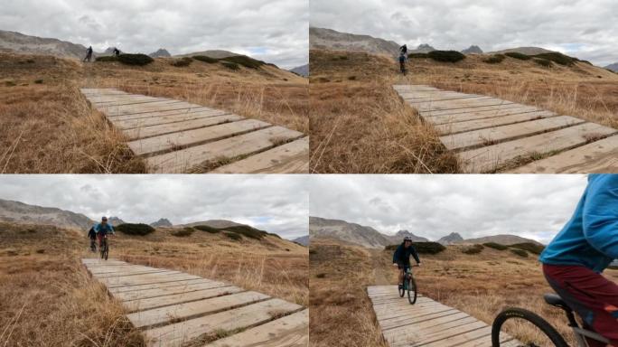 山地自行车手在山地草甸横穿木板路