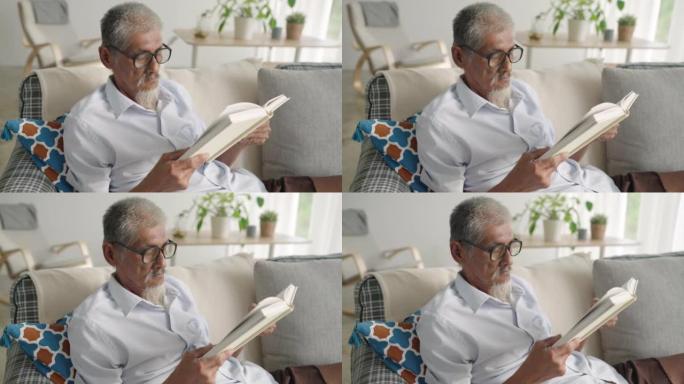 亚洲资深老人白发老人早上在家坐在沙发上看书，爱书人