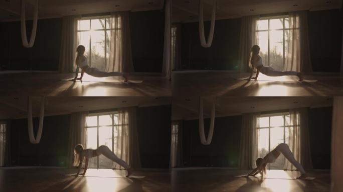 一名年轻女子在阳光下以慢动作练习瑜伽。透过窗户的光线，阳光
