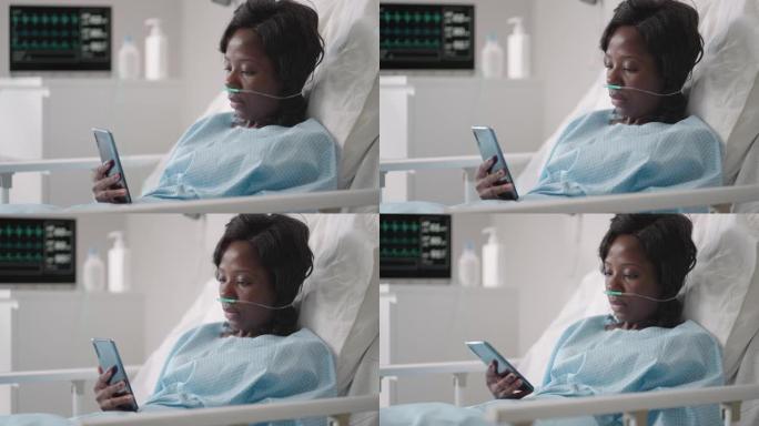 一名年轻女子躺在医院病房时在手机上写了一条信息。一名非洲女孩躺在病房里，病房里戴着口罩与心电图和氧气