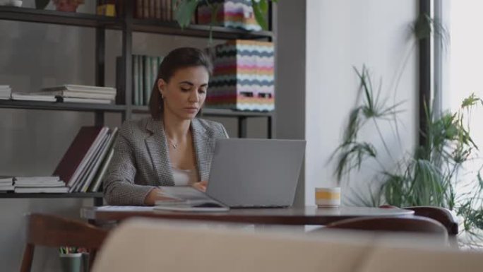 女人在家工作时使用笔记本电脑阅读短信。女人在办公室使用笔记本电脑工作学习。女商人在工作场所打字笔记本