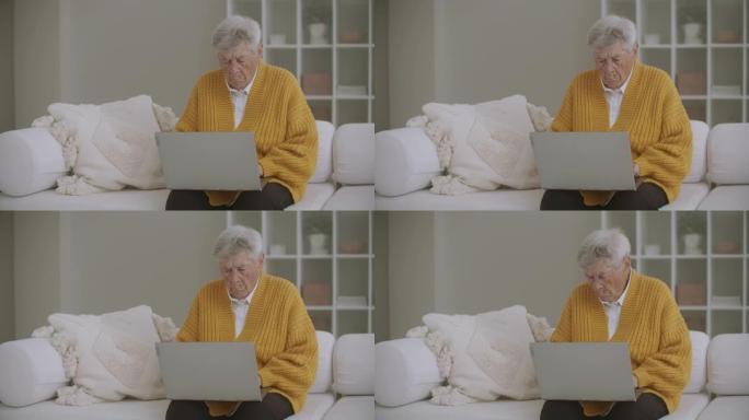 坐在沙发上的一位老妇人在键盘上打印了一条信息。奶奶用笔记本电脑