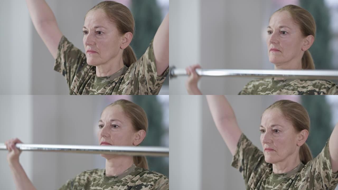近距离肖像集中动机的军事妇女在室内工作。中年白人女兵训练举重。健身和兵役。