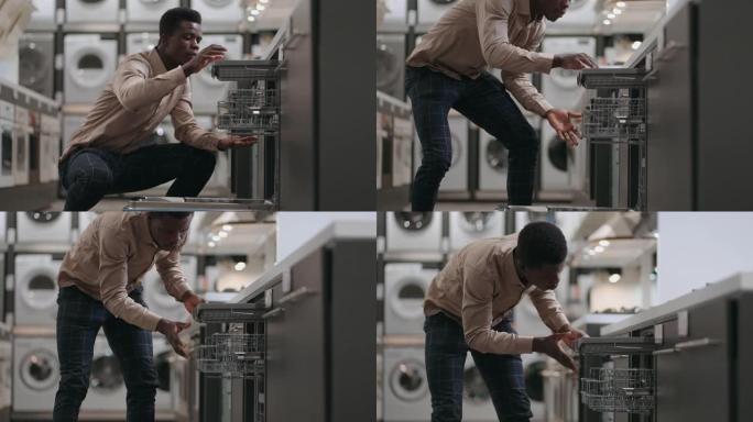 在带洗碗机的部门家电商店购物，年轻的黑人正在查看现代厨房设备，自动洗碗机