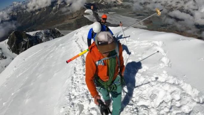 一队登山者沿着欧洲阿尔卑斯山的冰盖斜坡移动。使用绳索和攀爬设备