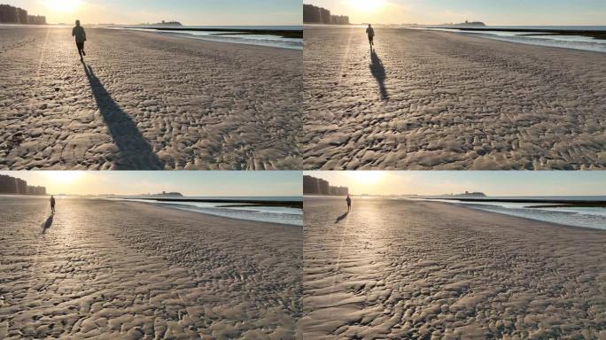 男子在空旷的海滩上奔跑的鸟瞰图