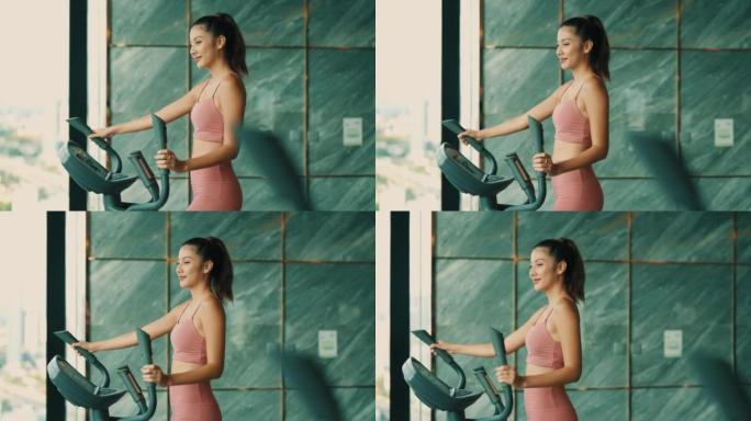 美丽的女人在健身房用椭圆步行机锻炼