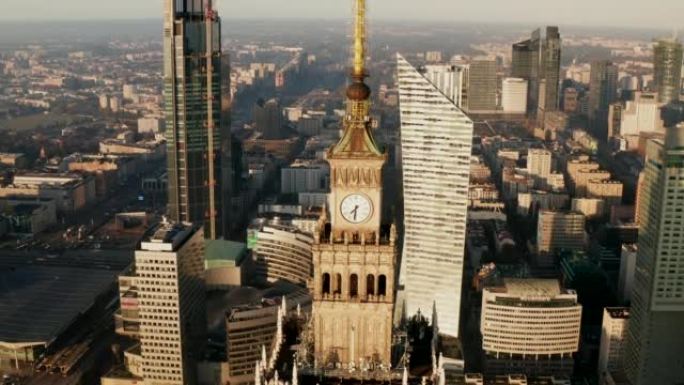 高层PKIN大楼顶部带有塔钟的尖顶空中下降镜头。背景中的现代高层建筑。波兰华沙