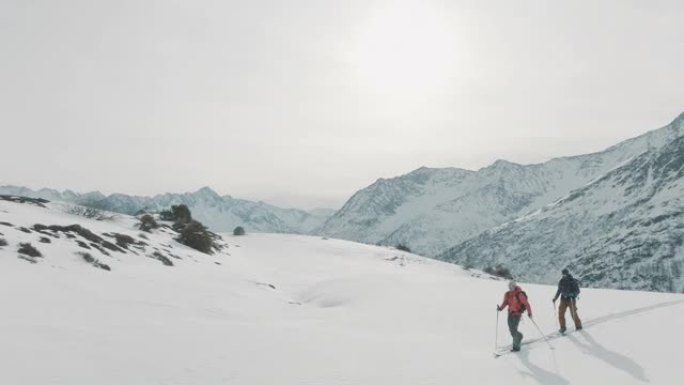 两名滑雪者在雪山上徒步旅行的空中无人机拍摄