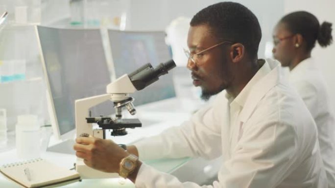 带有显微镜的非洲民族科学家。背景中的计算机屏幕