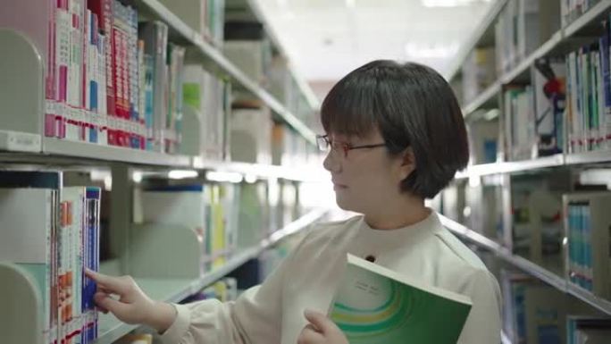 亚洲妇女在图书馆的书架上找到并阅读一本书