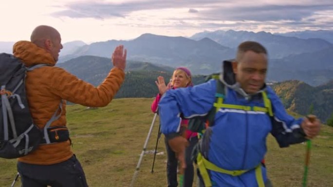 登山队到达山顶，和他们的登山队长击掌