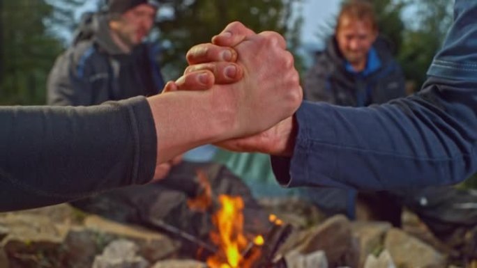 两个男人在森林里的篝火前做G锁握手