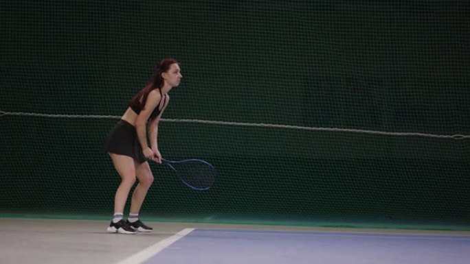 女选手在室内球场打网球，等待发球和球拍击球，慢动作全程射门