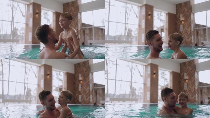 学龄前男孩和他的父亲在游泳池里游泳，快乐的孩子和父亲在家庭健康中心
