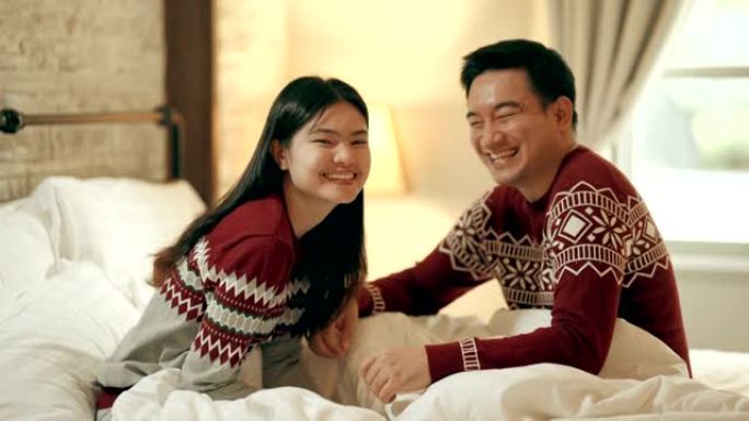 假期里，夫妻俩看着相机坐在床上庆祝圣诞节。