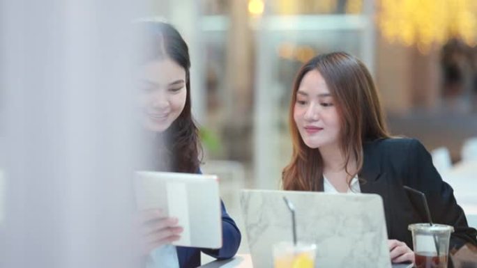 咖啡馆里的两名亚洲商界女性在会议期间微笑着玩得开心。
