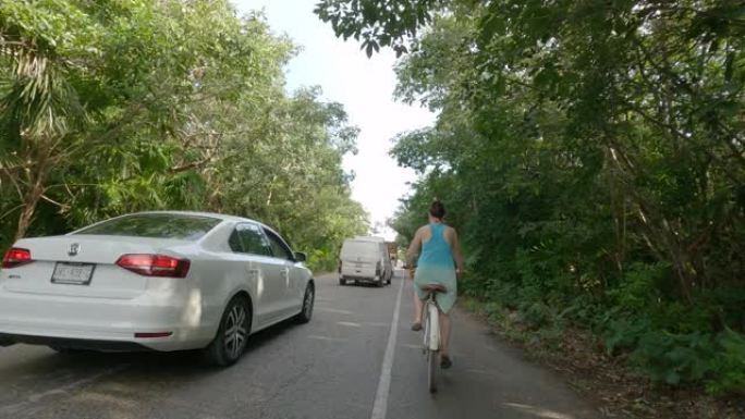 女人沿着丛林道路骑自行车