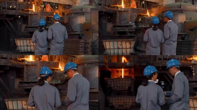男女工程师在铸造厂交谈，同时观察钢水的浇注