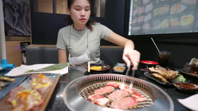 女人在餐馆吃日式烤菜。