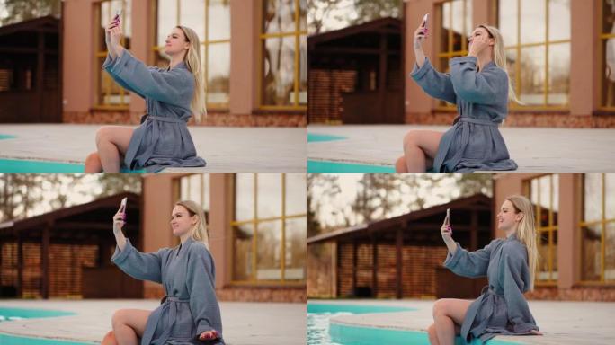 穿着礼服的漂亮女人在带开放式游泳池的水疗酒店休息，用智能手机自拍