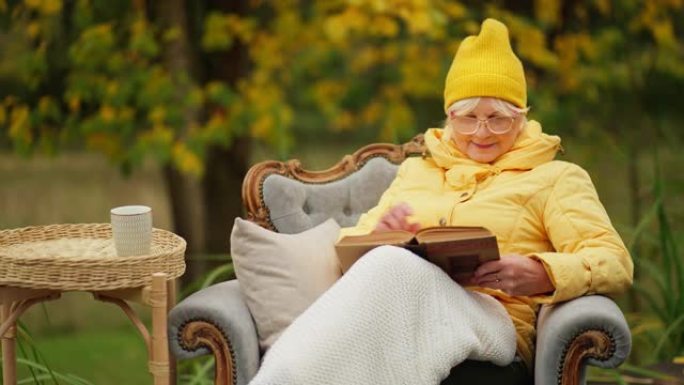 生病的老年妇女病人在外面的椅子上看书